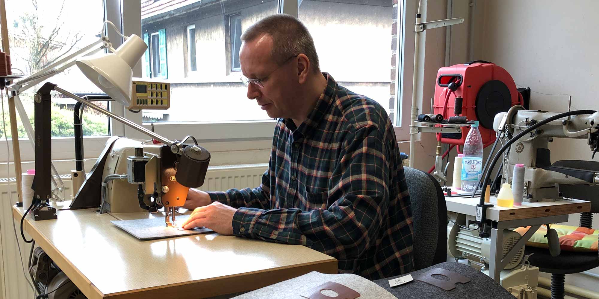 Ein Mann sitz an einer Nähmaschine und näht hochwertige Lederteile