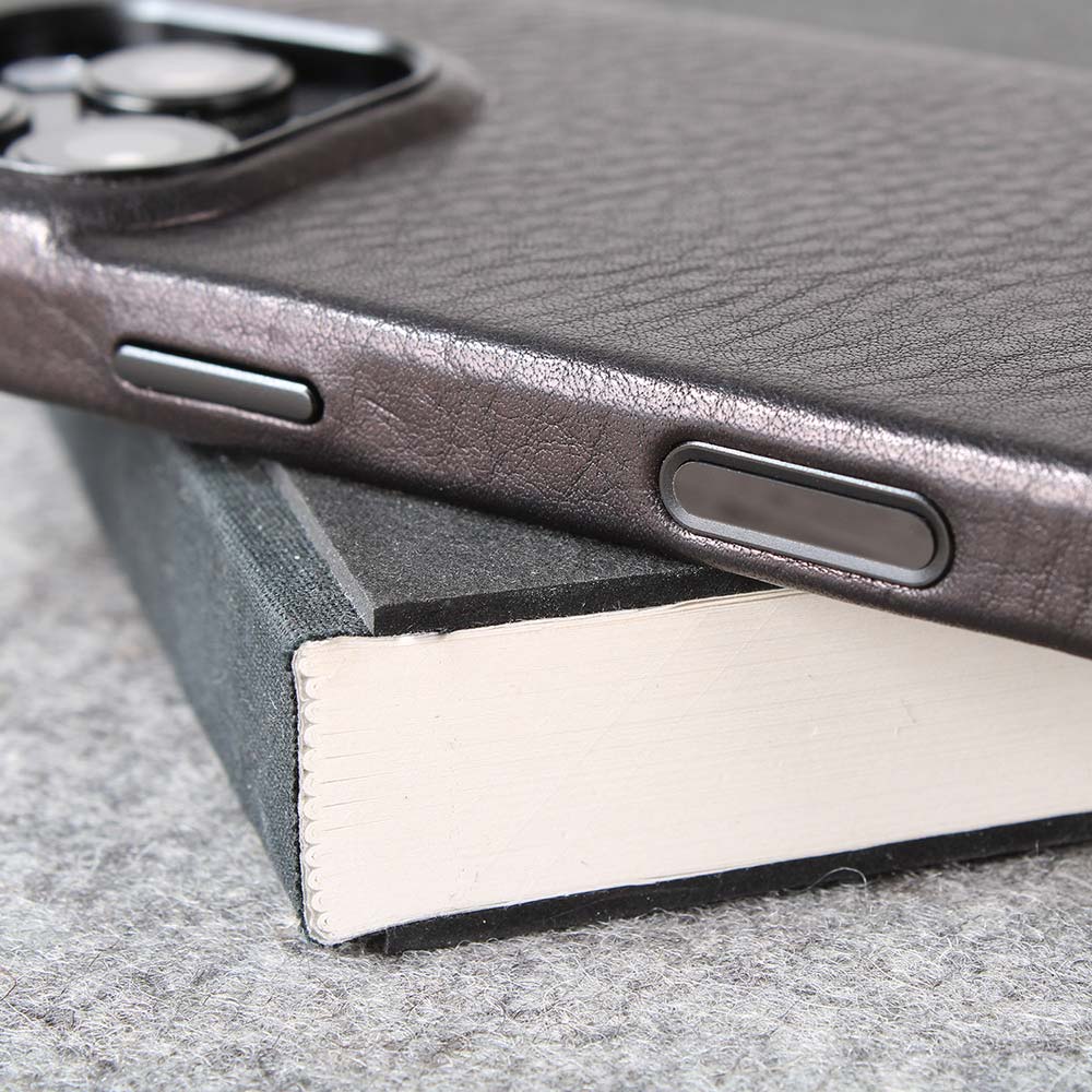 Auf einem Schreibblock liegt eine hochwertige iPhone 16 Pro Hülle mit Kamerasensor Knopf aus schwarzem Leder von Goodwilhelm