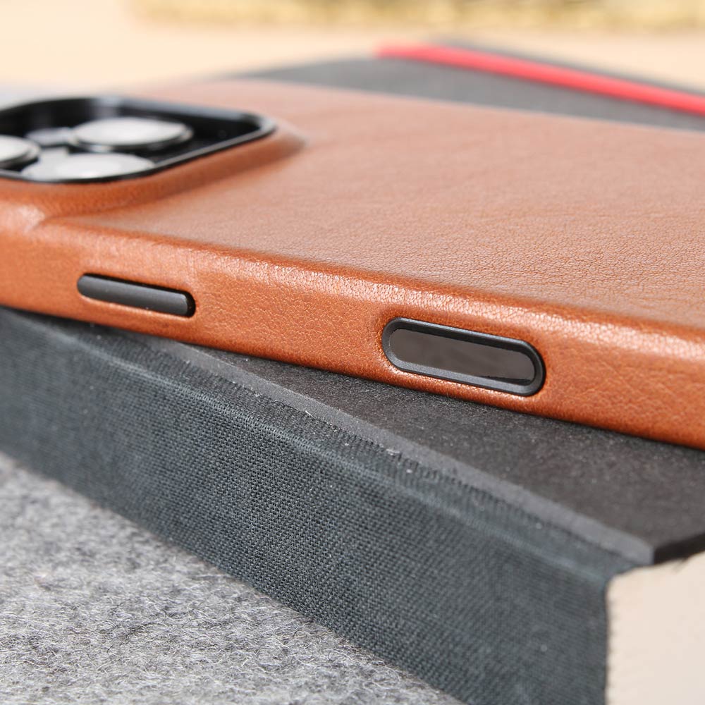 Auf einem Schreibblock liegt eine hochwertige iPhone 16 Pro Hülle mit Kamerasensor Knopf aus cognacfarbenem Leder von Goodwilhelm