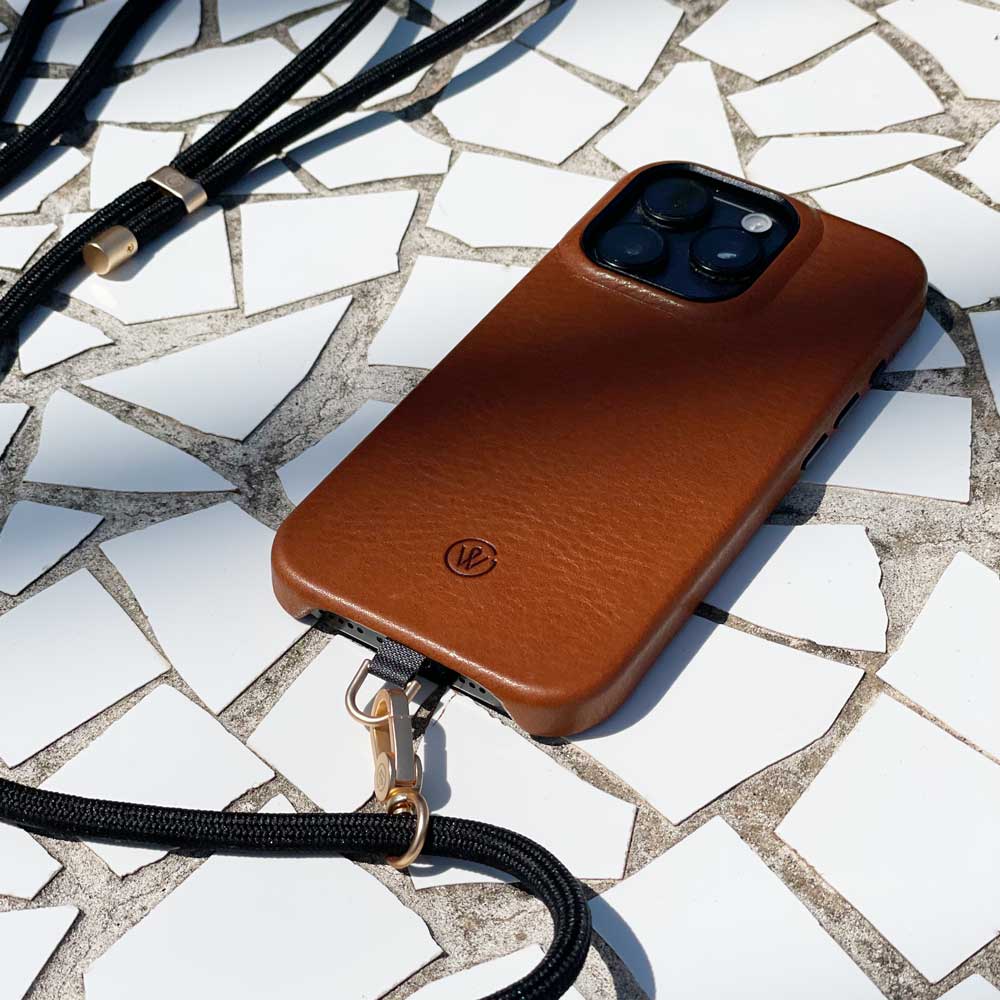 Good Wilhelm Handykette Handyband schwarz mit goldenem Karabiner, Band liegt auf Stein