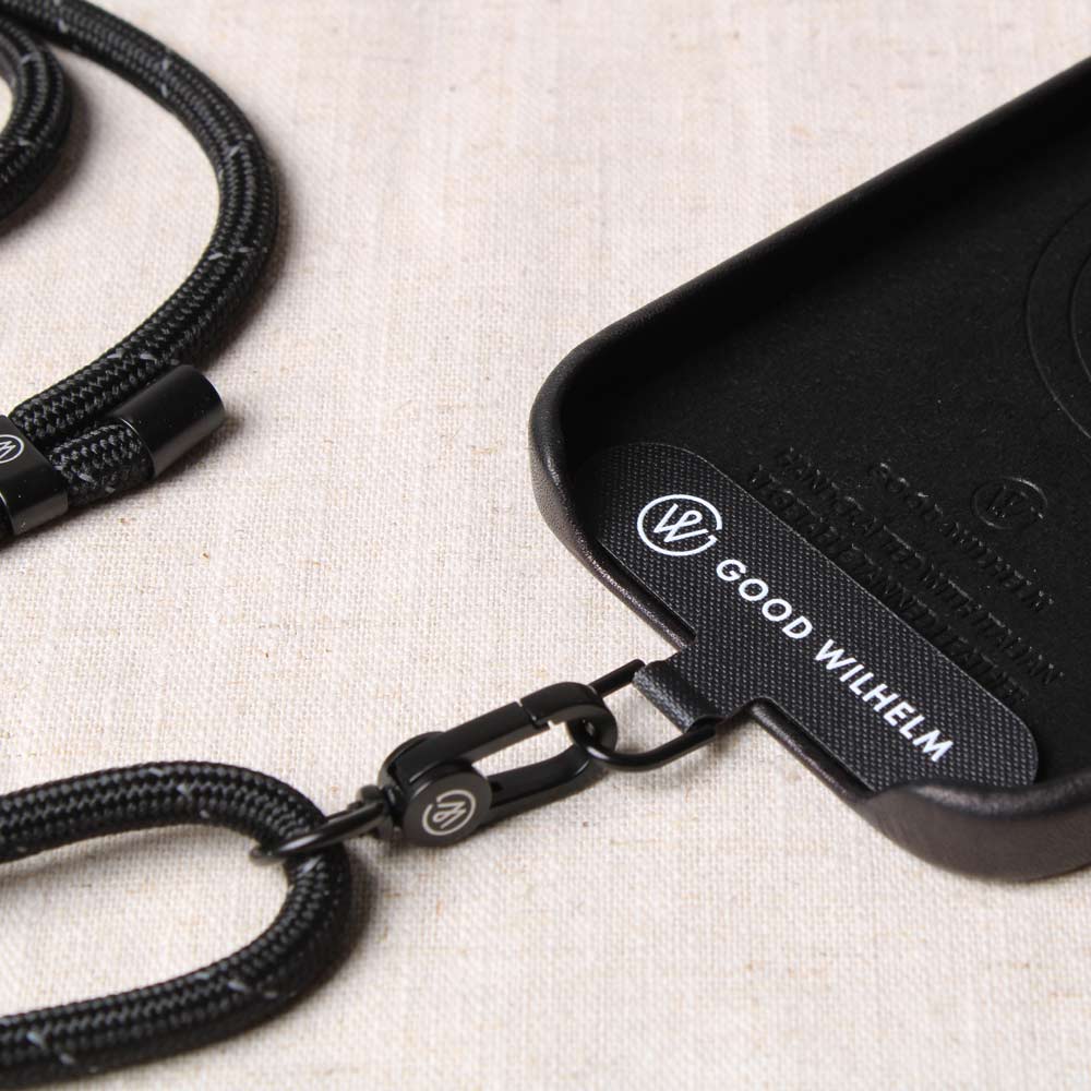 Good Wilhelm Handykette Handyband schwarz mit Reflektorstreifen und Befestigungselement auf Tisch