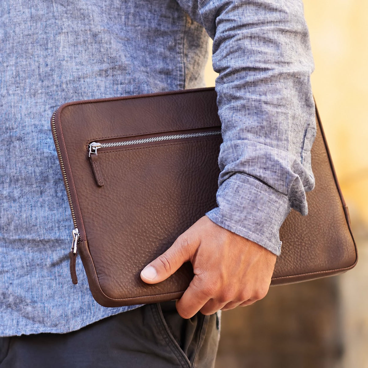 iPad Pro 13" Tasche aus dunkel braunem Leder von Good Wilhlem wird von einem Mann unter dem Arm getragen