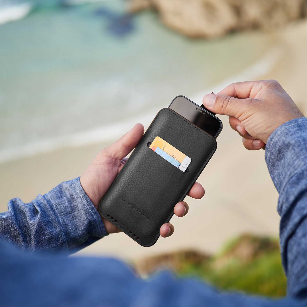 iPhone Leder Sleeve in Schwarz von Good Wilhelm in der Hand – Elegante pflanzlich gegerbte iPhone Hülle mit praktischer Ziehhilfe für einfaches Herausziehen des Smartphones.