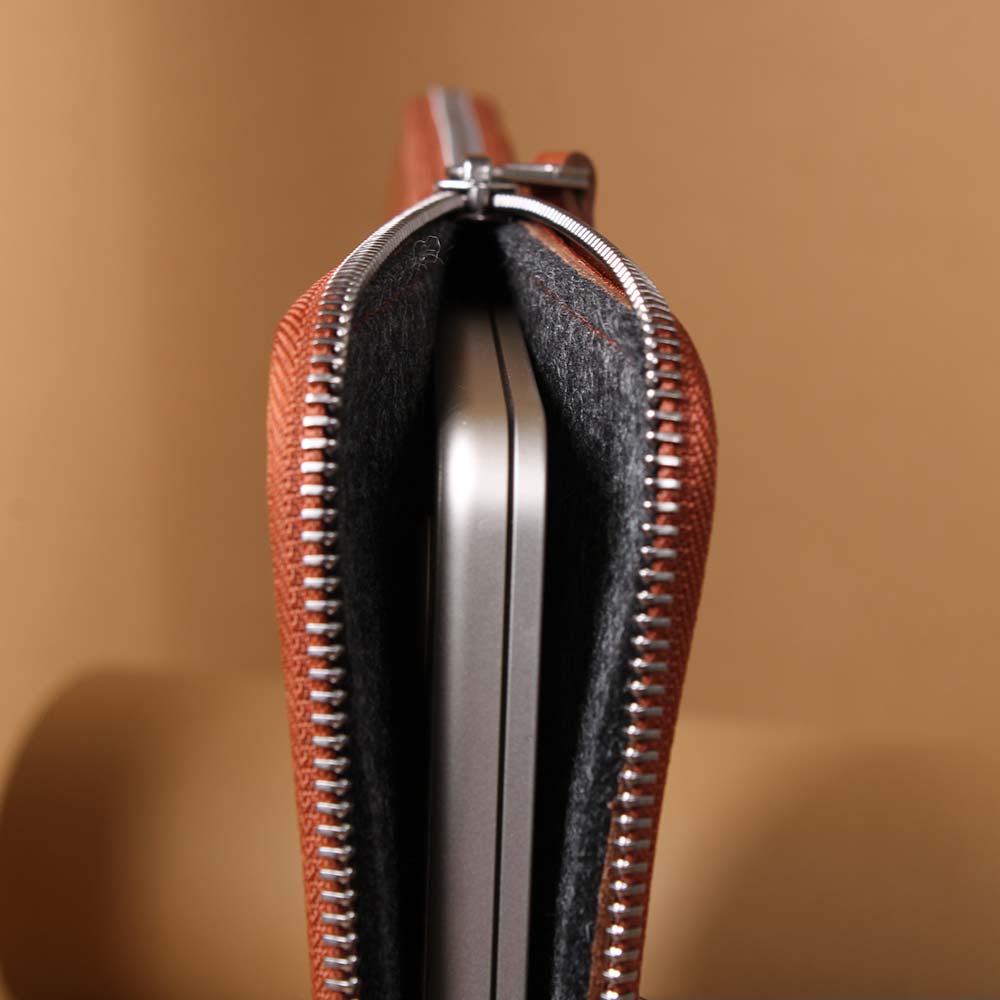 Ein Macbook steckt in einer Hülle, die mit einem Reißverschluss gewchlossen wird