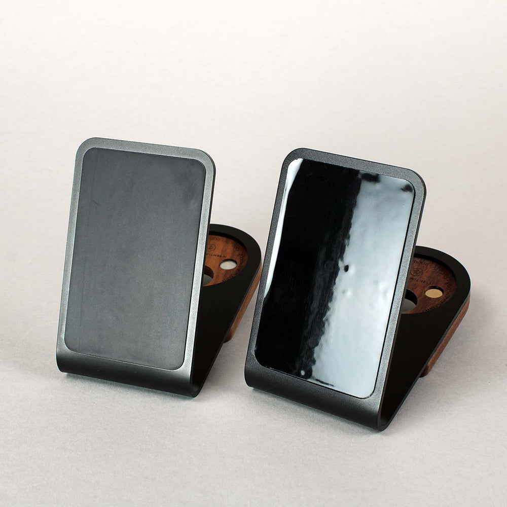 Auf einem Tisch liegen zwei Magsafe Halter aus Aluminium mit Antirutschpad und Saugnapffolie