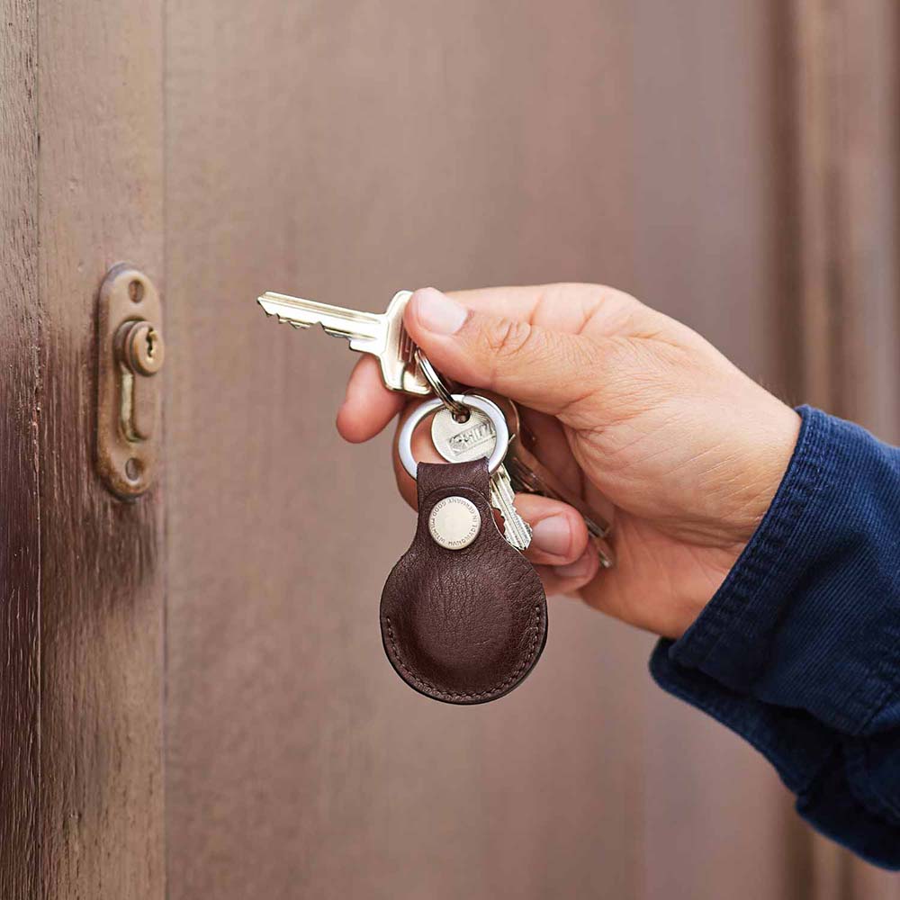 Eine Hand ist gerade dabei mit einem Schlüssel mit Schlüsselanhänger eine Tür aufzuschließen