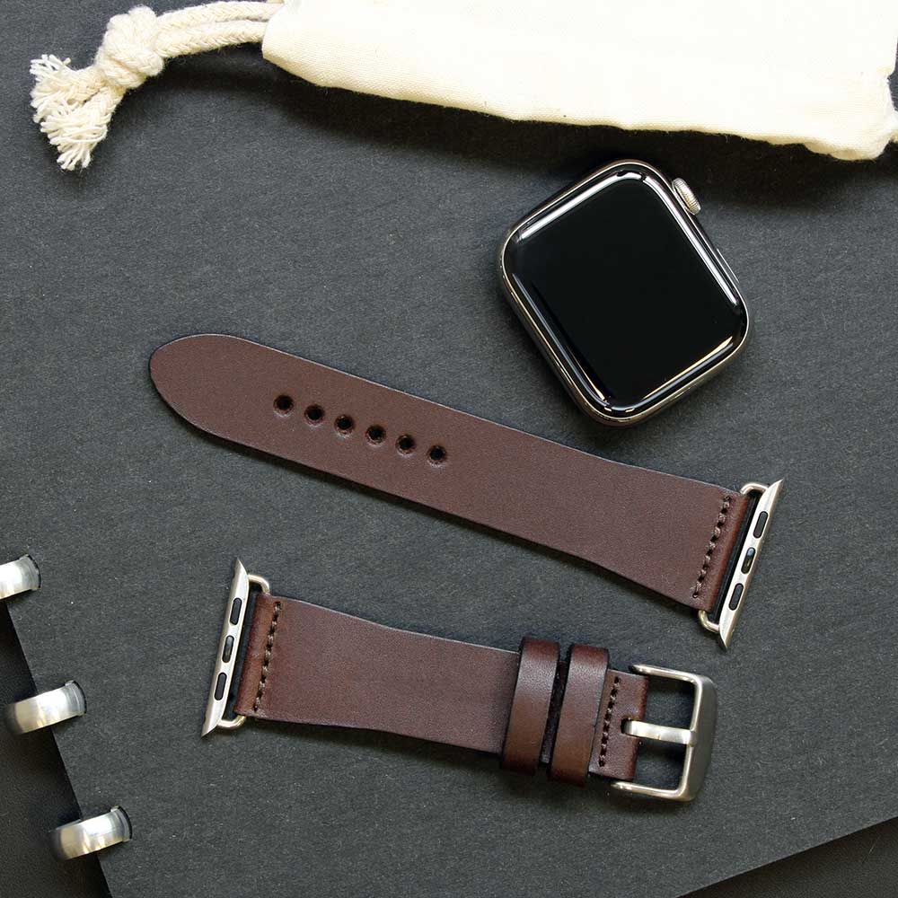 Ein Lederarmband für die Apple Watch in dunkelbraunem Leder liegt uaf einem Buch