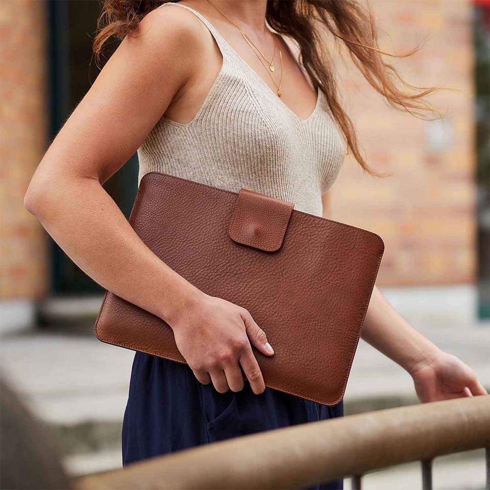 Eine Frau trägt ein ipad Pro Sleeve in dre Frabe Cognac unter dem Arm von Goodwilhelm