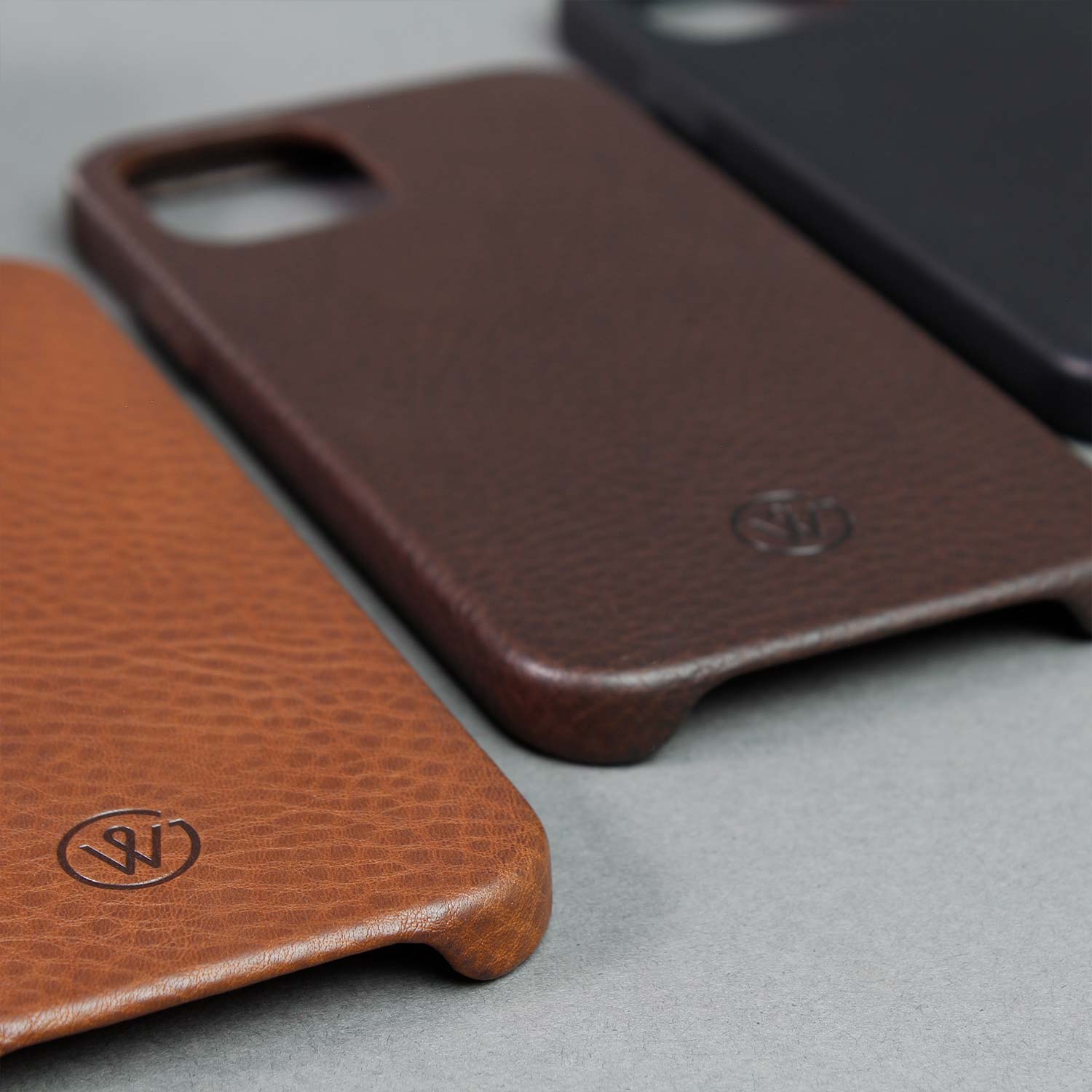 iPhone Hüllen BRUNO von GoodWilhelm in den Farben Cognac, Chocolate und Black liegen nebeneinander