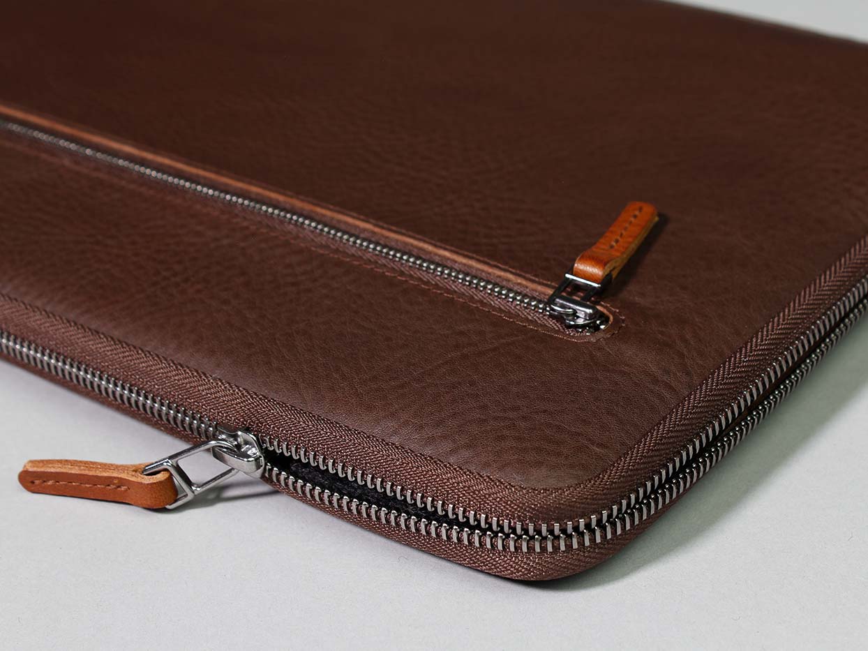 Auf einem Tisch liegt eine Dunkelbraune Ledertasche für das Microsoft Surface Laptop