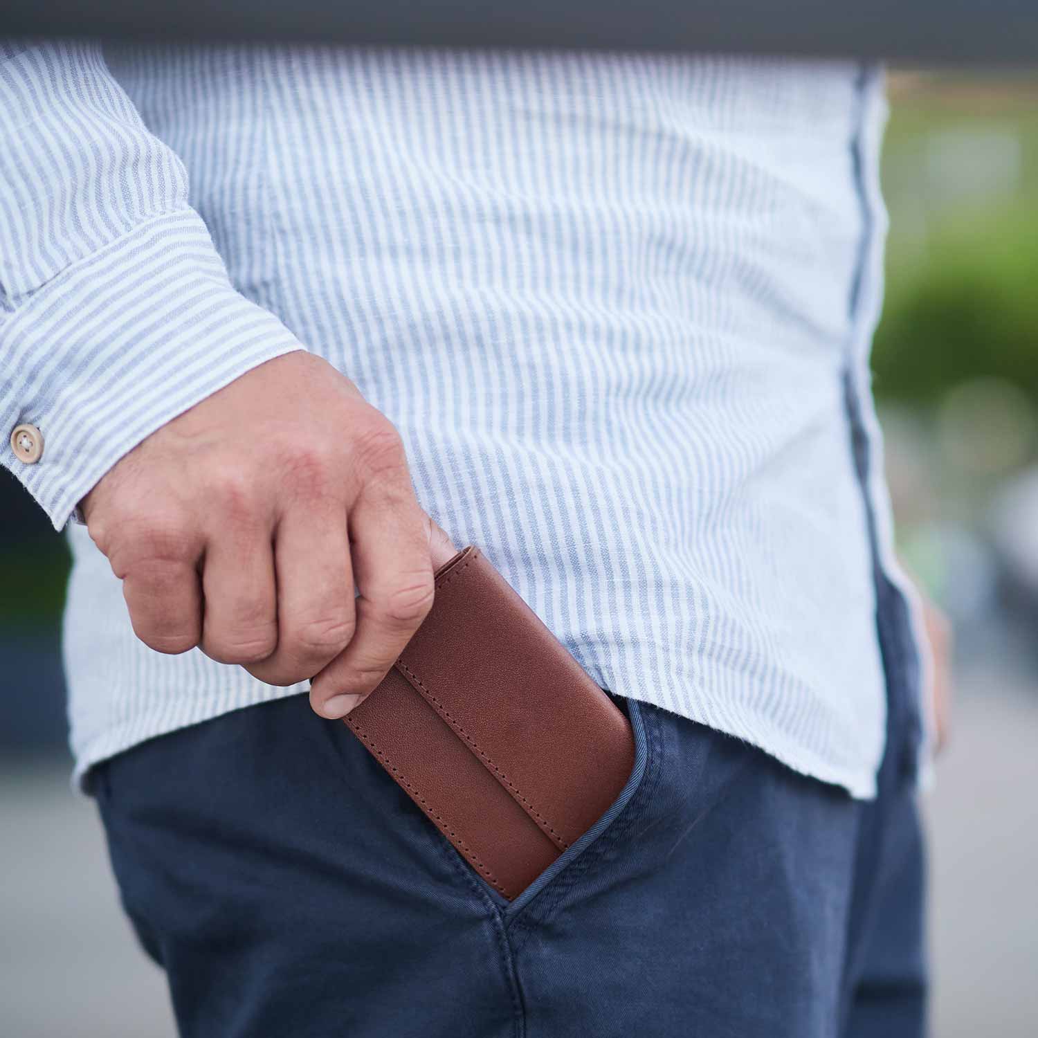 Mann steckt mini Portemonnaie OTTO von Goodwilhelm in der Farbe cognac in die Hosentasche