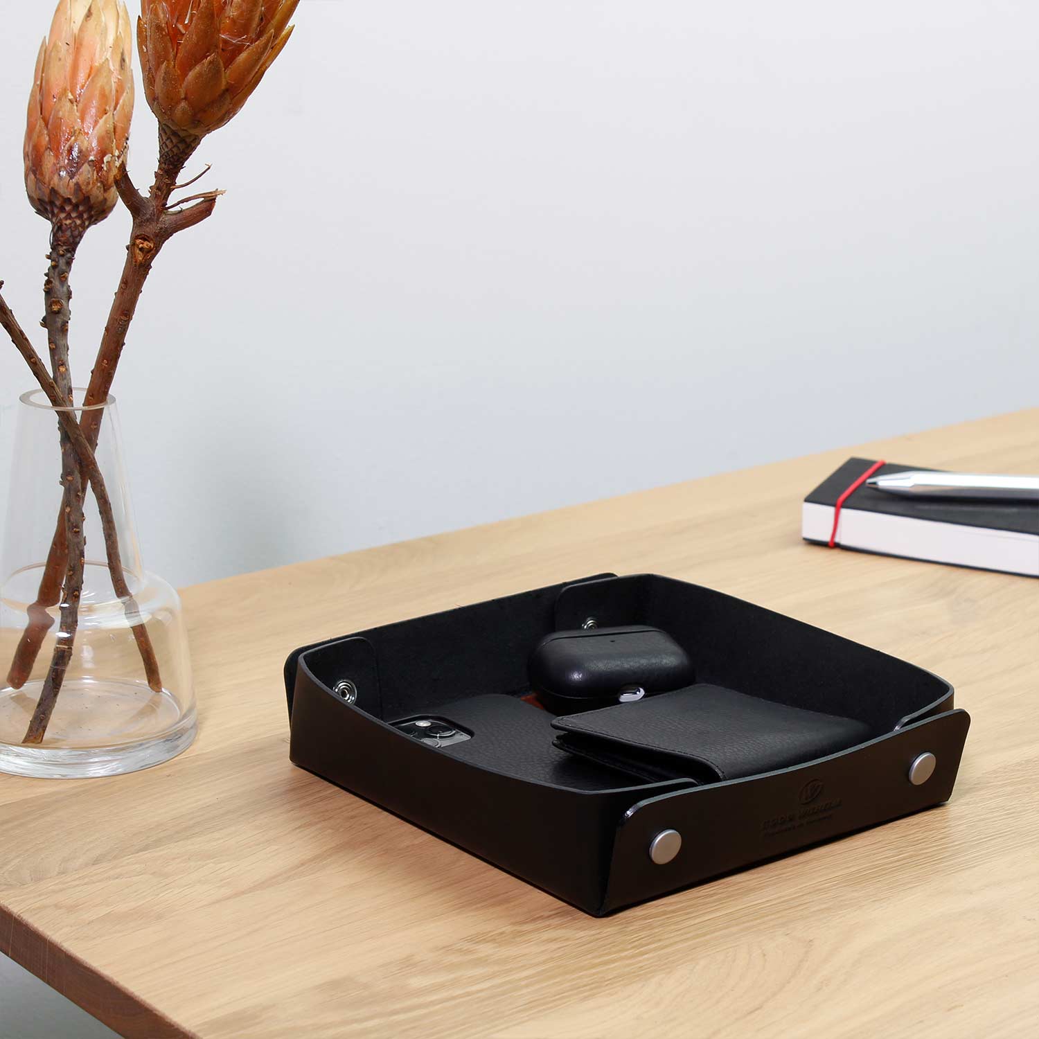 Taschenleerer Leder Schwarz von Goodwilhelm in der Farbe black mit AirPods, Portemonnaie und Handy drin