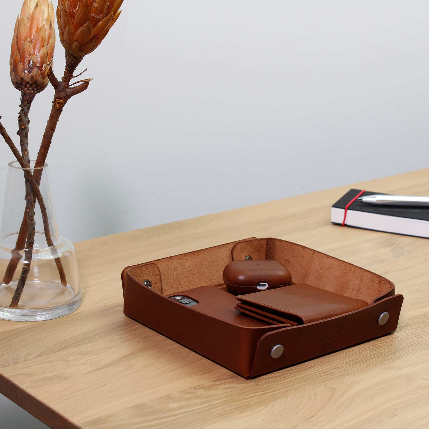 Taschenleerer aus Leder von Goodwilhelm in der Farbe cognac mit AirPods, Portemonnaie und Handy drin