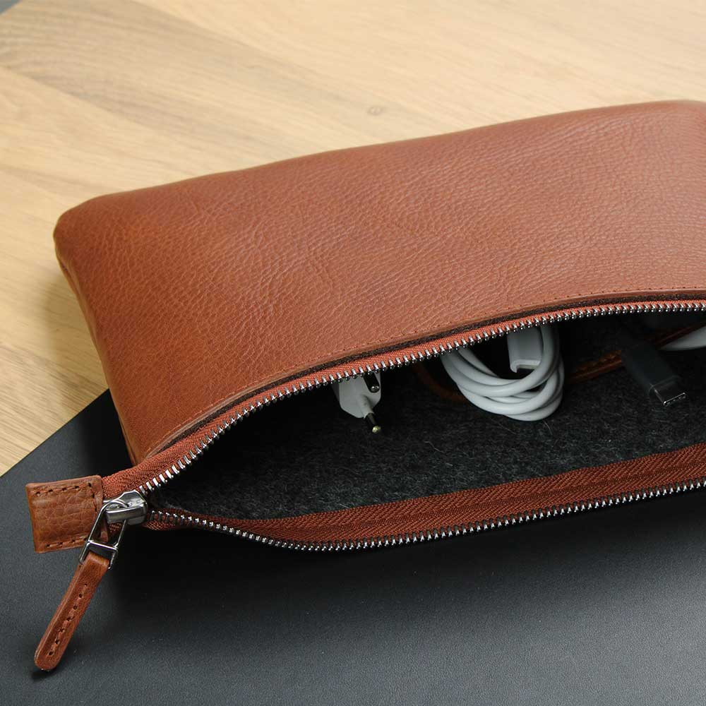 Auf einem Schreibtisch liegt eine Banktasche aus Leder in Hellbraun